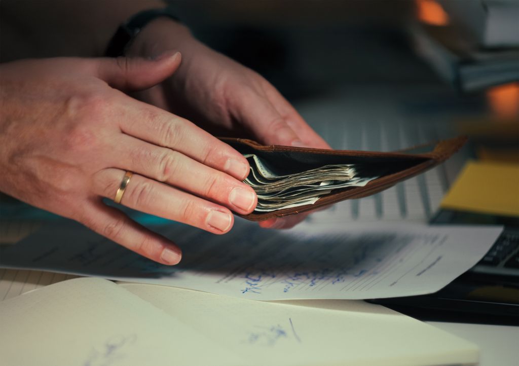 Hands holding an open wallet filled with cash above documents, indicating paying twice for HR consultancy support.